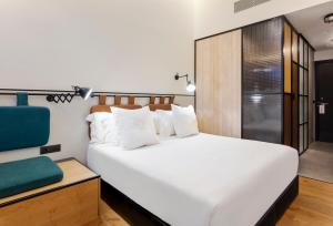 a bedroom with a large white bed and a chair at One Shot Tabakalera House in Donostia-San Sebastián