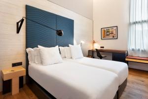 a bedroom with a large white bed with a blue headboard at One Shot Tabakalera House in Donostia-San Sebastián