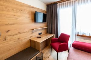 a hotel room with a red chair and a tv at Hotel Restaurant Silbersand in Riederalp