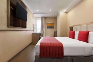 a hotel room with a large bed with red pillows at Ramada by Wyndham Bishkek Centre in Bishkek