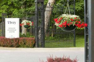a black gate with two hanging baskets of red and white flowers at Ivey Spencer Leadership Centre, a Dolce by Wyndham in London