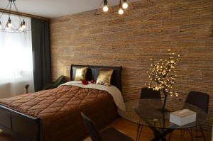 锡纳亚Sinaia Apart的卧室设有砖墙、一张床和一张玻璃桌