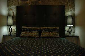 a bedroom with a large black bed with two lamps at Casa Do Povo in Seia