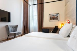 a hotel room with a bed and a chair and a desk at One Shot Tabakalera House in Donostia-San Sebastián