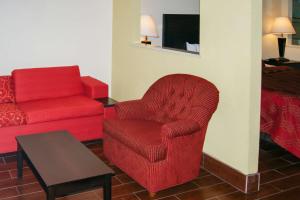 a living room with a red chair and a red couch at Econo Lodge Inn & Suites West - Energy Corridor in Houston