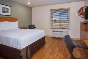 um quarto com uma cama, uma secretária e uma janela em WoodSpring Suites Grand Junction em Grand Junction