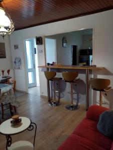 a living room with a kitchen and a bar with stools at Gite du village in Estréboeuf