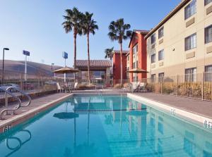een zwembad voor een gebouw met palmbomen bij Holiday Inn Express Westley, an IHG Hotel in Westley