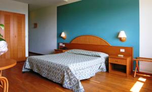 ein Schlafzimmer mit einem Bett und einer blauen Wand in der Unterkunft Hotel Cavalieri in Passignano sul Trasimeno