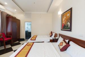 a hotel room with two beds and a red chair at Titanic 2 Hotel in Hanoi