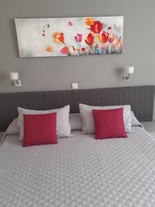 Una cama con almohadas rojas y una pintura encima. en Irene's Apartments, en Limassol