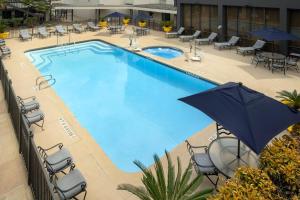 a large swimming pool with chairs and an umbrella at Crowne Plaza San Antonio Airport, an IHG Hotel in San Antonio