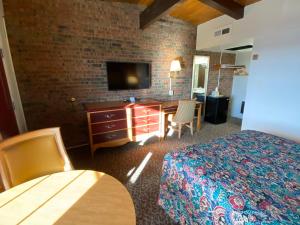 Habitación de hotel con cama, escritorio y TV. en Dunes Inn Alamosa en Alamosa