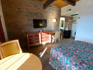 Habitación de hotel con cama, escritorio y TV. en Dunes Inn Alamosa, en Alamosa