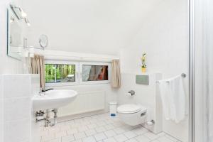 a white bathroom with a toilet and a sink at Restaurant & Hotel Baumhaus Hagen in Sassnitz