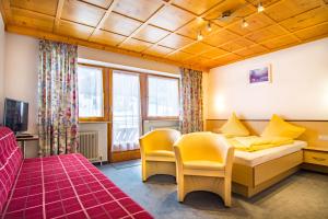 a hotel room with a bed and chairs in it at Apart Bergblick in Ischgl