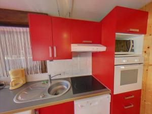 una pequeña cocina con armarios rojos y fregadero en EA115 - 2 Pièces 6 Pers proche centre des Carroz, en Les Carroz d'Araches