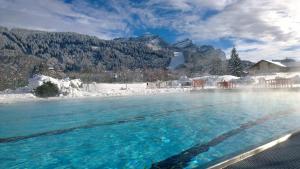 una piscina de agua con nieve y montañas al fondo en EA031 - Studette proche centre des Carroz, en Les Carroz d'Araches