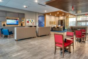 Holiday Inn Express & Suites - Omaha Downtown - Airport, an IHG Hotel في أوماها: لوبي مستشفى وكراسي حمراء وطاولة