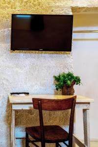 un tavolo con una sedia e una televisione su una parete di B&B PIAZZA SAN GIOVANNI - ESSENZE DELLA MURGIA ad Altamura