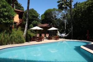 a swimming pool with tables and chairs and umbrellas at Pousada Catamara in Arraial d'Ajuda