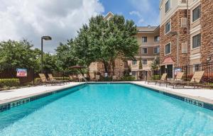 una piscina con sillas y un edificio en Staybridge Suites Austin Round Rock, an IHG Hotel en Round Rock