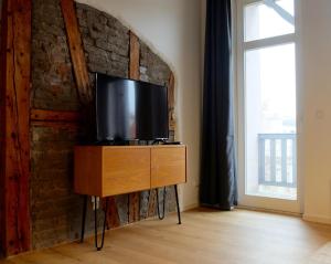 uma televisão numa cómoda num quarto com uma parede de tijolos em Altstadt Apartment Erfurt em Erfurt