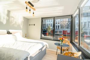 a bedroom with a bed and a table and windows at 2 Houseboat Suites Amsterdam Prinsengracht in Amsterdam