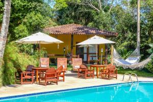 a group of chairs and tables with umbrellas next to a pool at Pousada Catamara in Arraial d'Ajuda