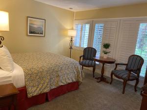 a bedroom with a bed, chair, desk and a television at Normandy Inn in Carmel