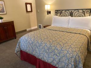 Schlafzimmer mit einem Bett mit einer blauen und weißen Bettdecke in der Unterkunft Normandy Inn in Carmel