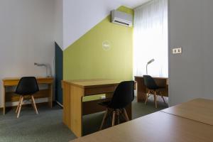 a room with a table, chairs and a desk at UniHo Hostel in Pavia