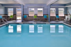 Una piscina con sillas y mesas en un edificio. en Holiday Inn Express Hotel & Suites North Kansas City by IHG, en Kansas City
