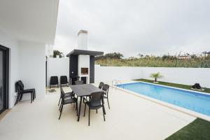 a patio with a table and chairs next to a swimming pool at Estrela de Salir - Holiday - By SCH in Salir de Porto