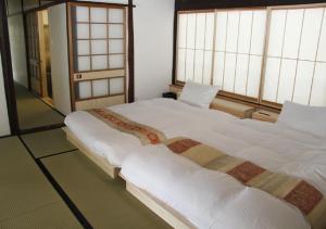 2 große Betten in einem Zimmer mit 2 Fenstern in der Unterkunft Setouchi Cominca Stays Hiroshima furousen / Vacation STAY 64497 in Shōbara