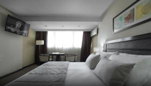a bedroom with a bed with white pillows and a window at Hotel 8 de Octubre in Buenos Aires