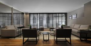 a living room with couches and tables and windows at Hotel 8 de Octubre in Buenos Aires