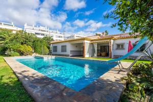 a swimming pool in front of a house at El Hidalgo Costa del Sol in Torre de Benagalbón