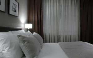a bedroom with a bed with white pillows and a window at Hotel 8 de Octubre in Buenos Aires