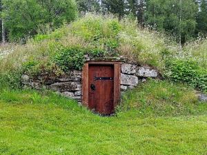 a stone wall with a wooden door in the grass at 8 person holiday home in STMARK in Östmark