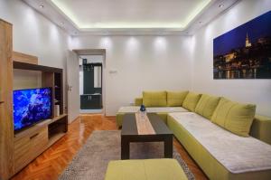ein Wohnzimmer mit einem Sofa und einem TV in der Unterkunft Balkanic Star Belgrade in Belgrad