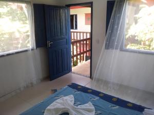 a bedroom with a blue door and a window at Hospedaria Cosanostra in Itaúnas