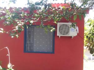 a red wall with a window with a fan at Hospedaria Cosanostra in Itaúnas