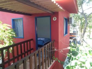 uma casa vermelha com janelas azuis e uma varanda em Hospedaria Cosanostra em Itaúnas