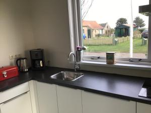 um balcão de cozinha com um lavatório e uma janela em Vissers Huus Hollum Ameland em Hollum