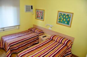 2 łóżka w pokoju z żółtymi ścianami w obiekcie Hostal El Jardín w mieście Benidorm