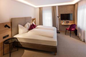 una camera d'albergo con due letti e una televisione di Hotel Hennersberg a Wörgl