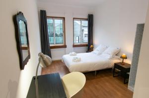 Un dormitorio con una cama y una mesa y dos ventanas. en Change The World Hostels - Porto - Santa Catarina, en Oporto