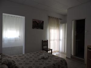 1 dormitorio con 1 cama, 1 silla y 1 ventana en Hospedaje Lisboa Algeciras, en Algeciras
