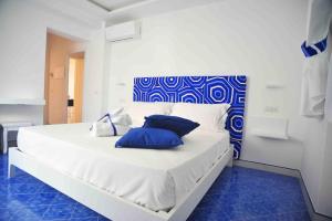 a white bed with blue pillows on it in a room at Matteo's House B&b in Amalfi